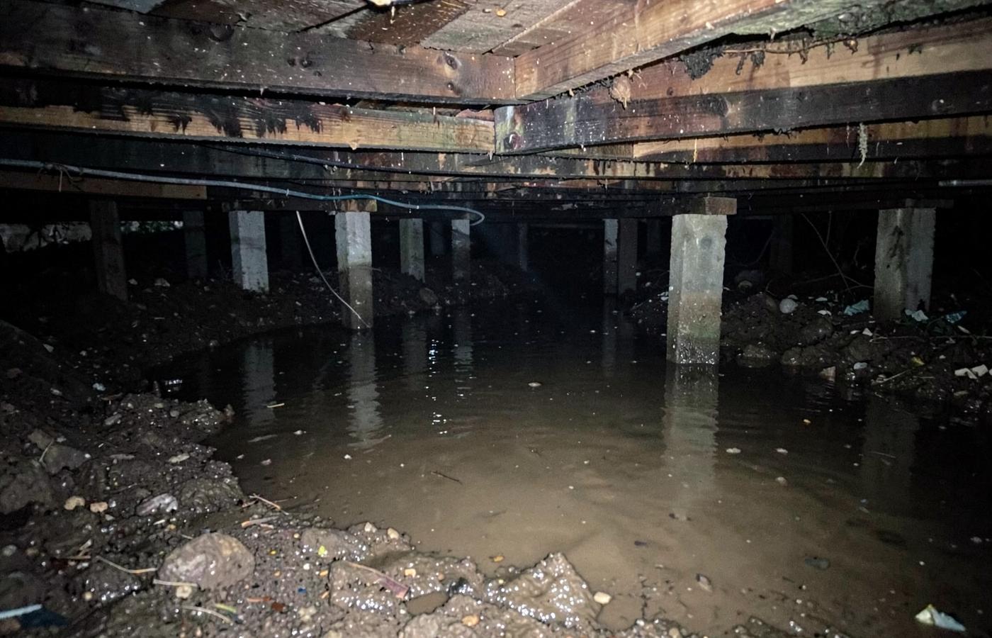 Standing water inside a residential crawl space over bare soil